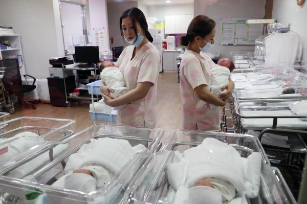신생아실에서 간호사들이 아기들을 돌보고 있다.