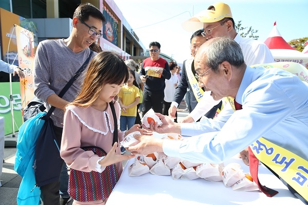 이승율 청도군수가 축제장에서 어린이에게 반시를 나누어 주고 있다.