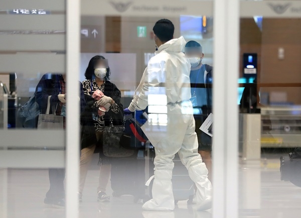 30일 인천국제공항 제2여객터미널에서 방역당국 관계자가 입국자들을 입국장으로 인솔하고 있다.