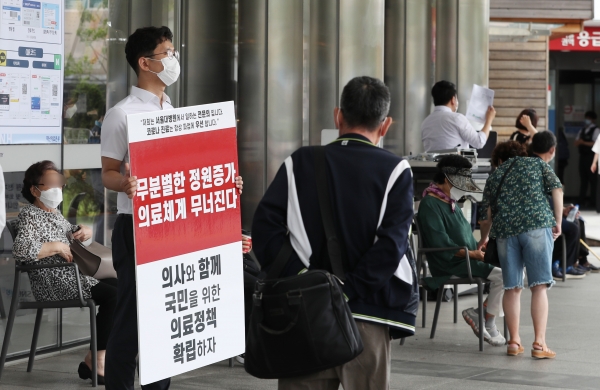 1일 서울 종로구 서울대병원 본관 앞에서 한 전공의가 정부의 의료정책에 반대하는 피켓을 들고 있다.