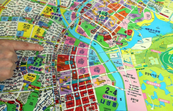 세종시의 한 공인중개사사무소에서 공인중개사가 지도를 보며 부동산 시장 동향을 설명하고 있다.