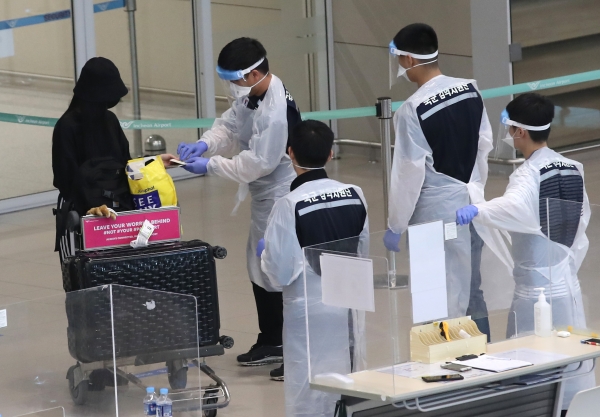 지난 21일 오후 인천국제공항 제2여객터미널에서 방역 관계자들이 해외 입국자들에게 동선을 안내하고 있다. (사진 뉴스1)