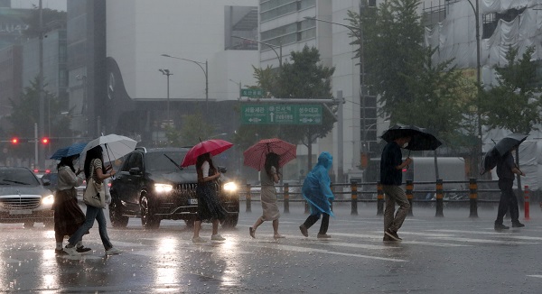 서울을 비롯한 중부지방에 호우특보가 내리며 많은 비가 내리고 있는 8일 서울 강남구 도산대로 횡단보도에서 우산을 쓴 시민들이 발걸음을 재촉하고 있다.