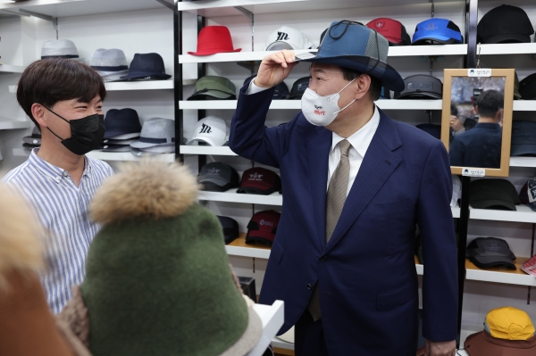 윤석열 대통령이 26일 오후 대구 중구 서문시장을 찾아 한 상점에서 모자를 써보고 있다.