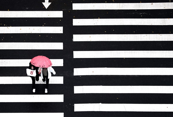비가 내린 18일 오후 서울 강남구의 한 횡단보도 위로 우산 쓴 시민들이 지나가고 있다.