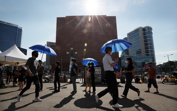 시민들이 22일 서울 중구 서울역 신종 코로나바이러스 감염증(코로나19) 임시선별검사소에서 파란색 양산을 쓰고 검사를 기다리고 있다.