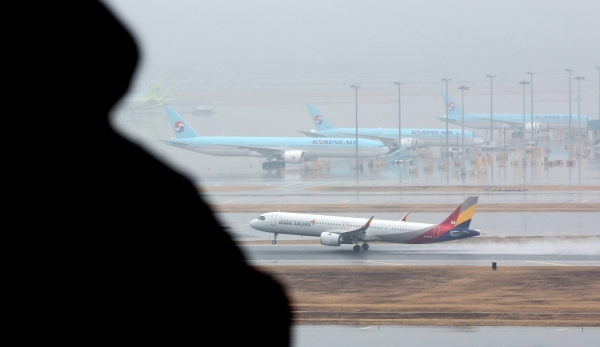 인천국제공항 계류장에 세워진 대한항공 항공기 앞으로 아시아나 항공기가 이륙하고 있다.